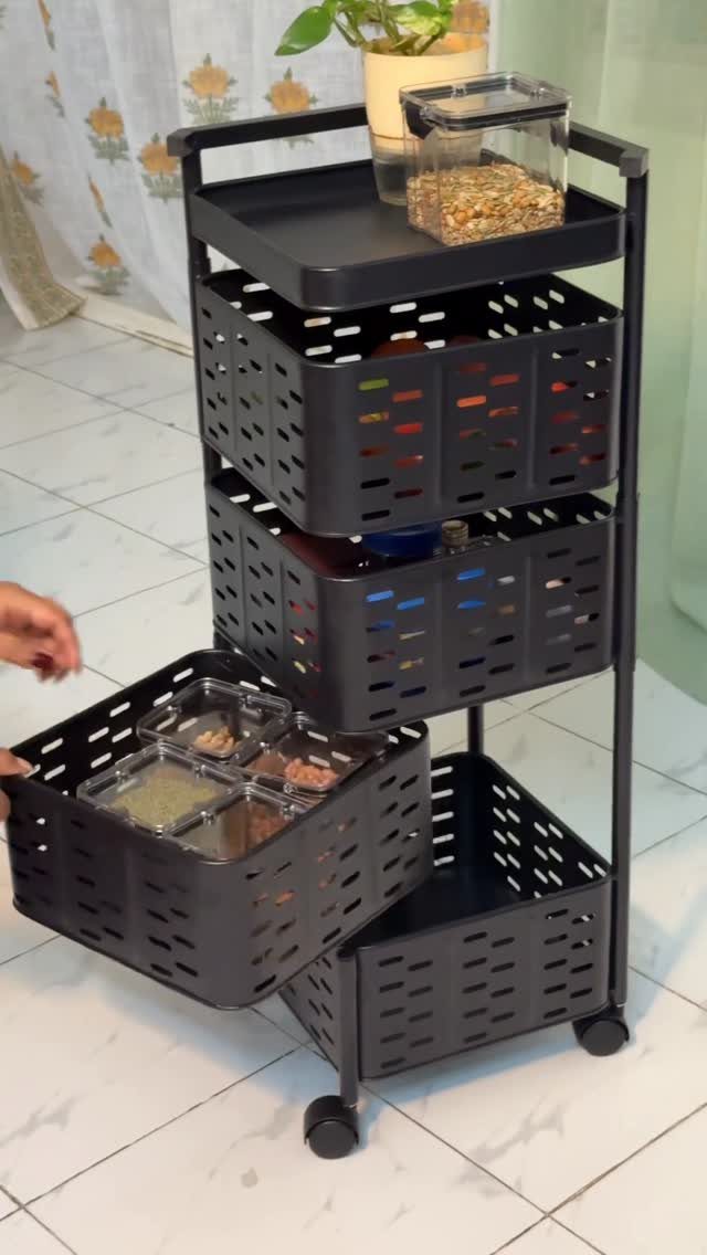 Black rolling storage cart with perforated bins and clear containers on white tile.