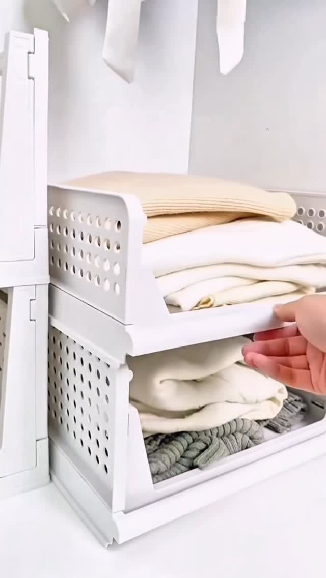 White perforated plastic storage bins holding folded beige and white clothes in a closet.