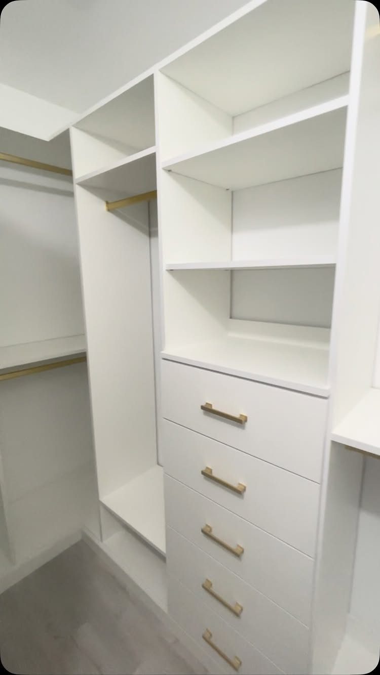 White custom closet system with open shelving, gold rods, and integrated drawers.
