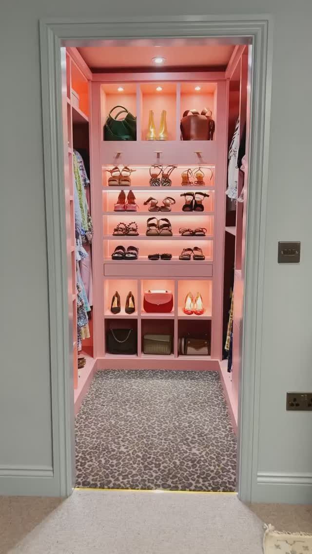 Pink walk-in closet with built-in shelving displaying shoes and handbags on leopard carpet