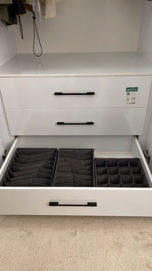 Open white closet drawer with grey fabric dividers organizing small items