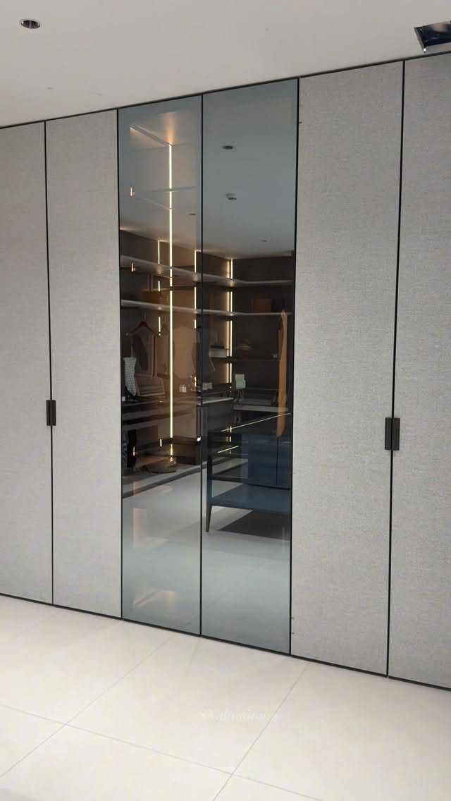 Modern walk-in closet with glass doors and integrated LED lighting strips on shelves