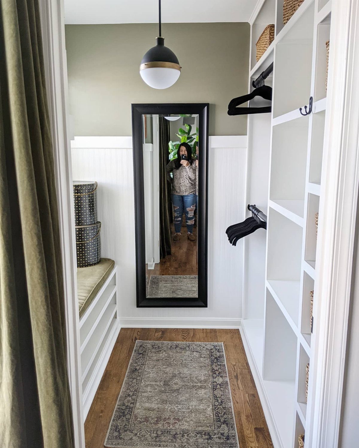 Small walk-in closet with white built-in shelving extending to the ceiling and mirror.