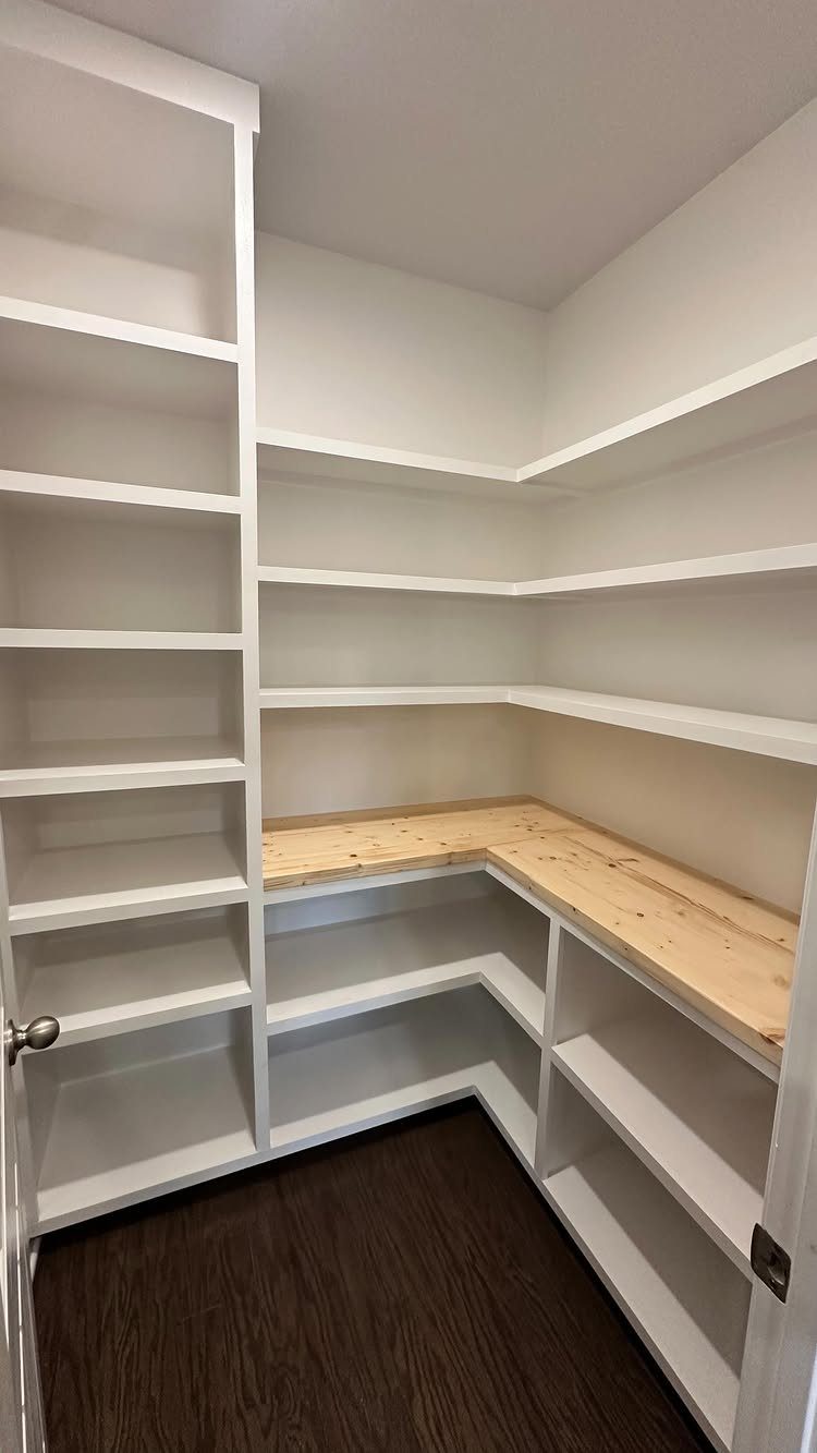 White built-in shelving and wooden countertop in a small walk-in closet organizer
