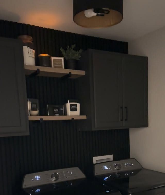 Black slatted accent wall in a laundry room with dark grey cabinets and shelves.