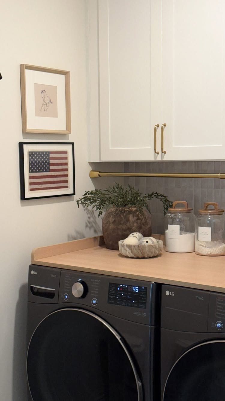 Dark grey washing machines under a light wood countertop with white upper cabinets.