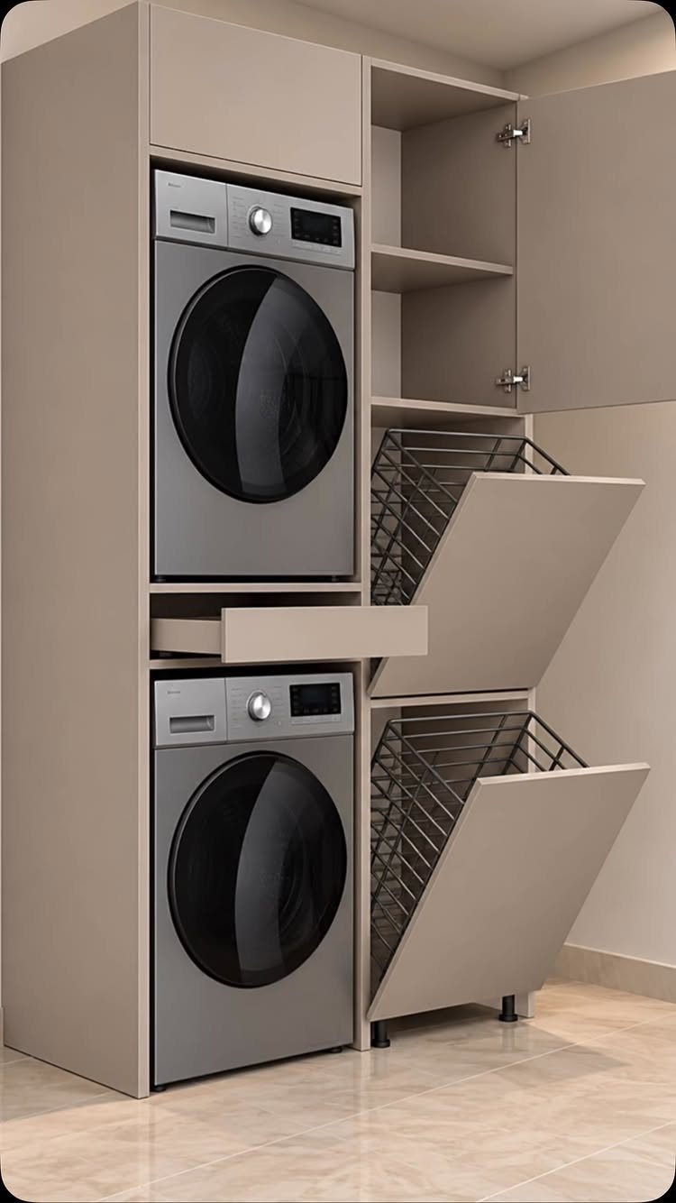 Beige laundry cabinet with stacked silver washer and dryer and pull-out hampers.