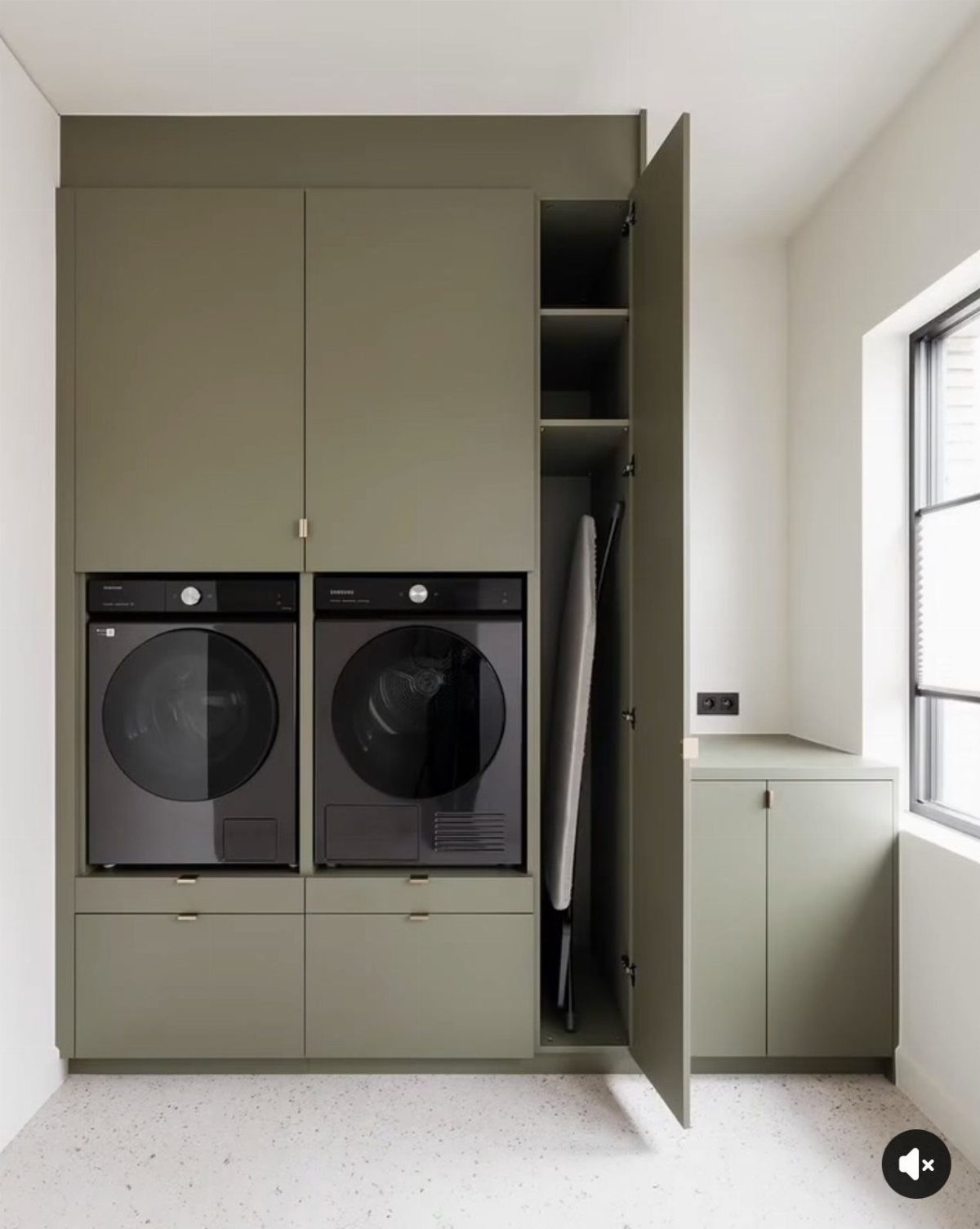 Black washer and dryer integrated into olive green cabinetry with overhead storage.