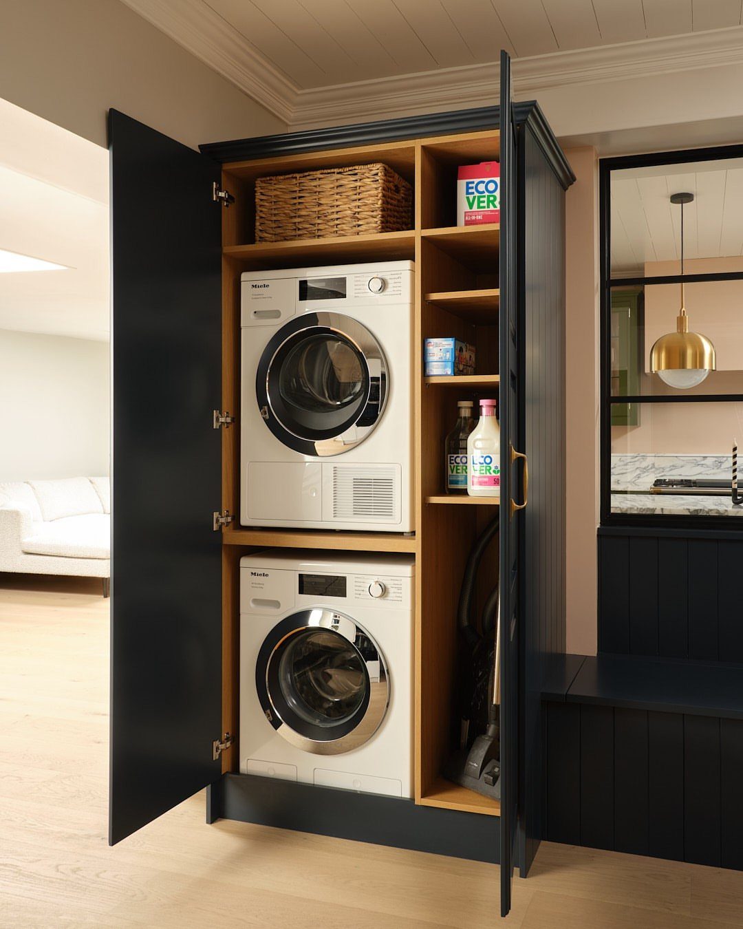 Stacked white washer and dryer units inside a dark blue storage cabinet.
