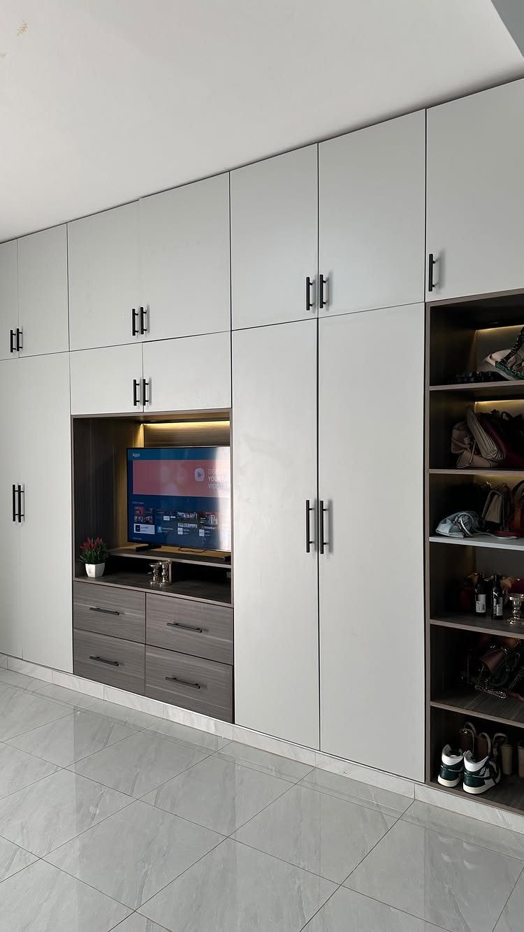 White built-in wardrobe with closed cabinets, a TV nook, and open shelving.