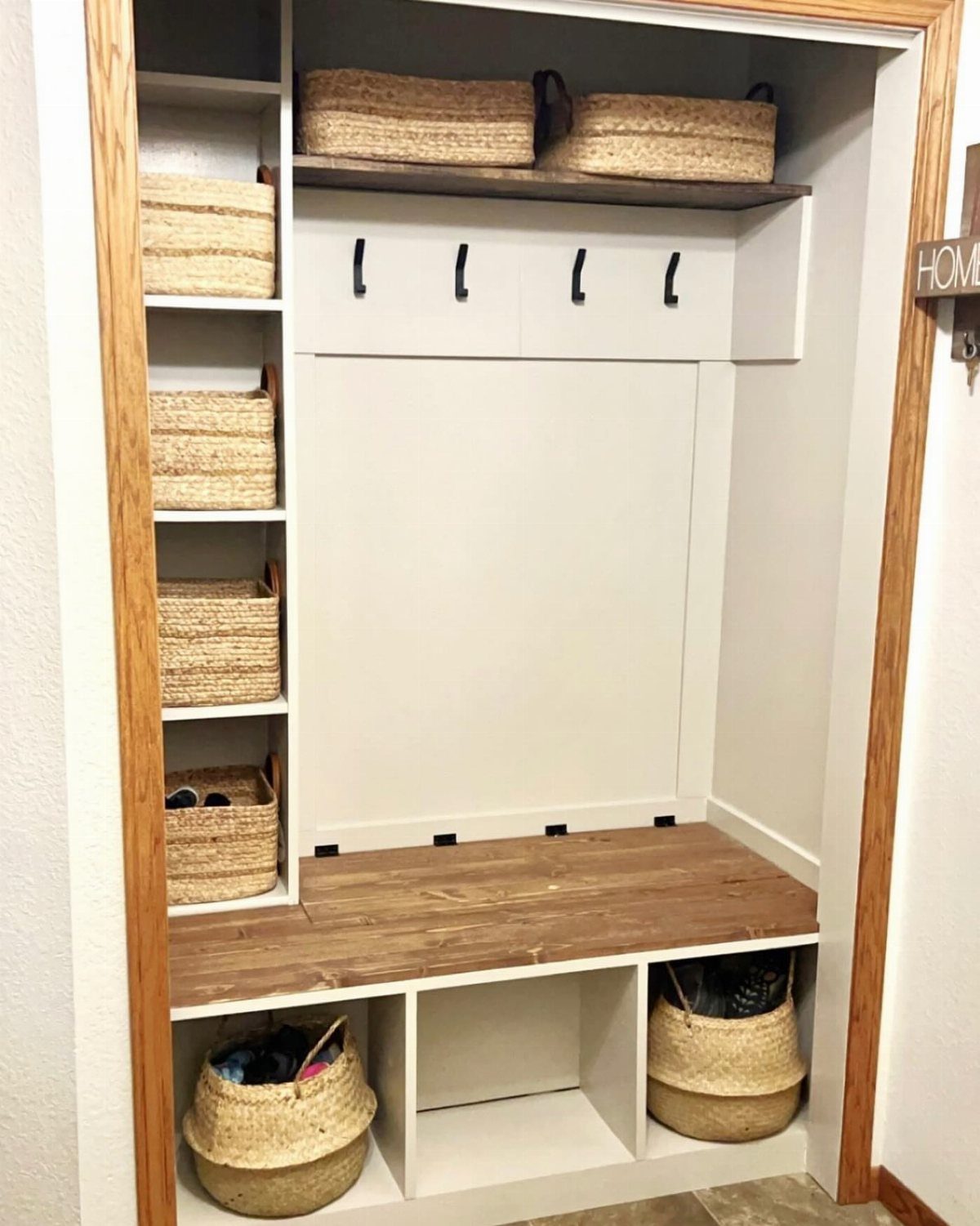 White built-in mudroom organizer with a wooden bench and woven storage baskets.