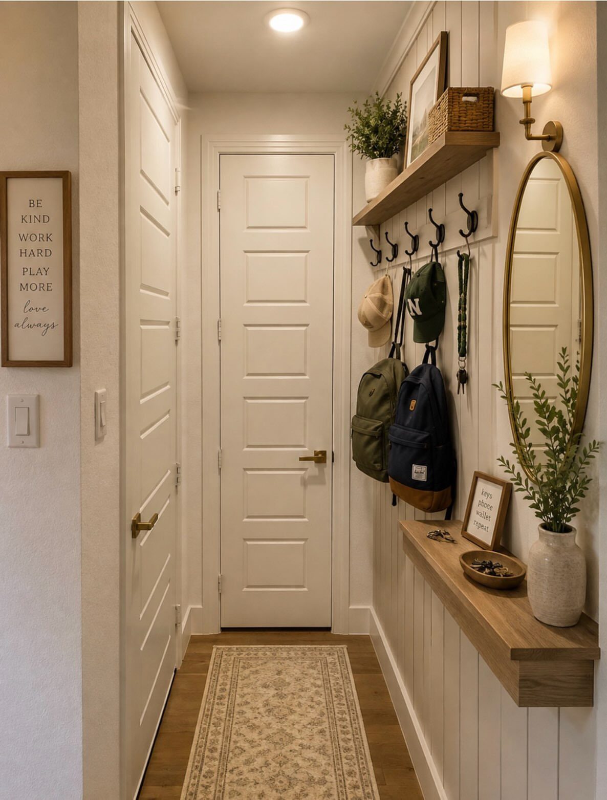 Wooden floating shelves and hooks in a white hallway mudroom with backpacks.
