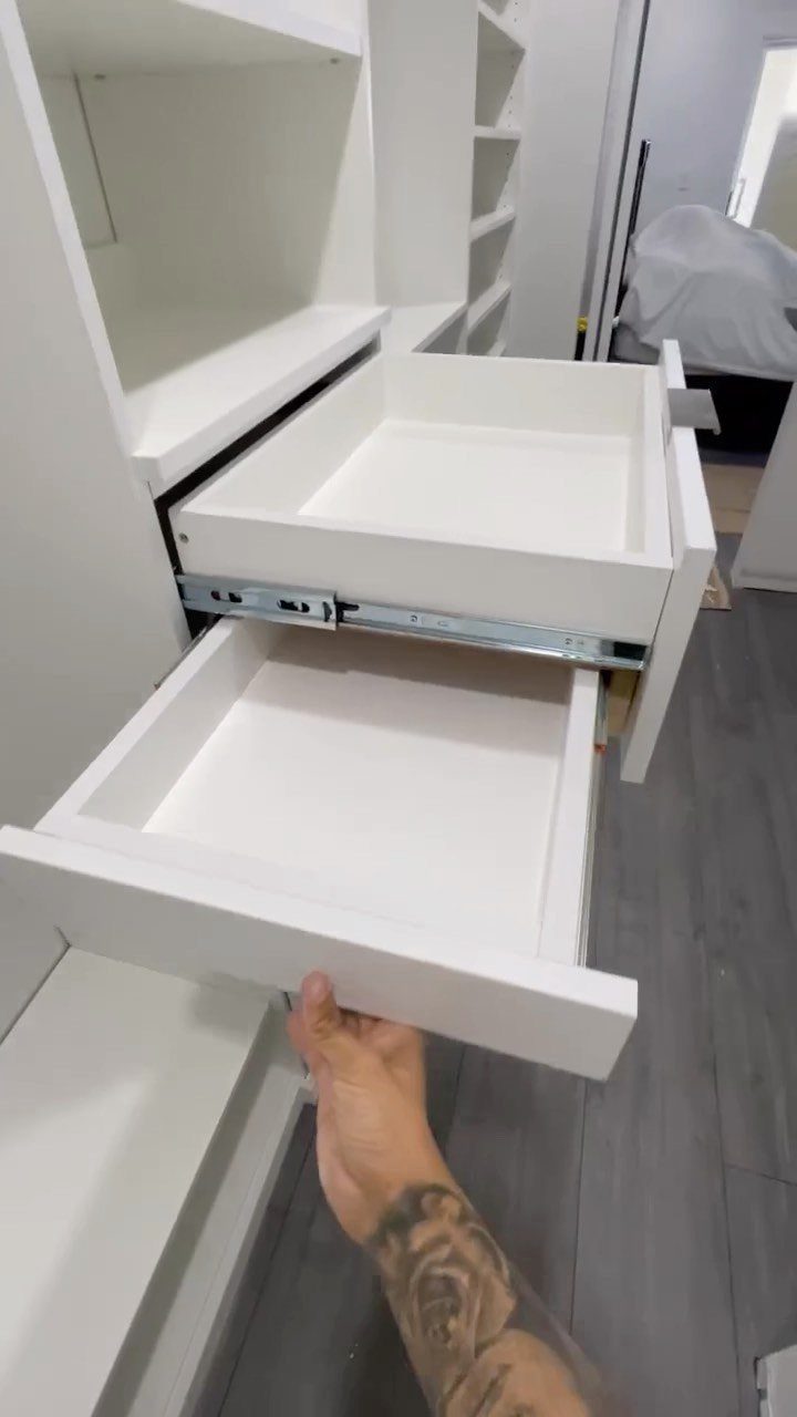 White built-in drawers being opened in a modern white shelving unit.