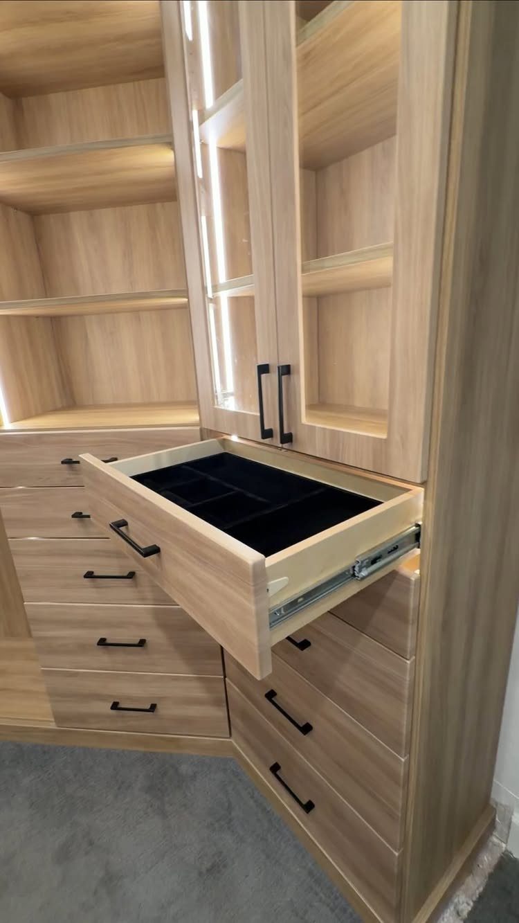 Light wood closet with an open drawer showing a black velvet organizer insert.