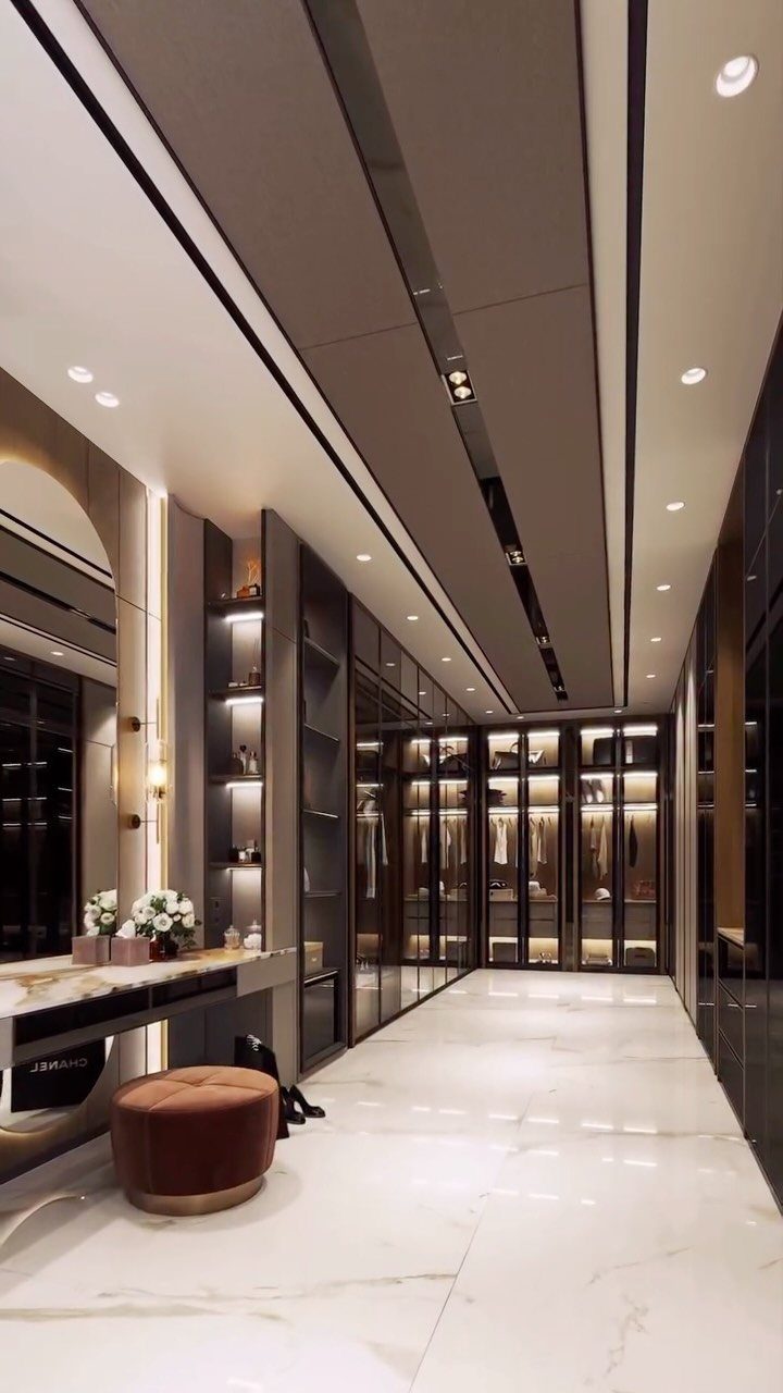 Large luxury walk-in closet with marble floors, dark shelving, and a velvet ottoman.