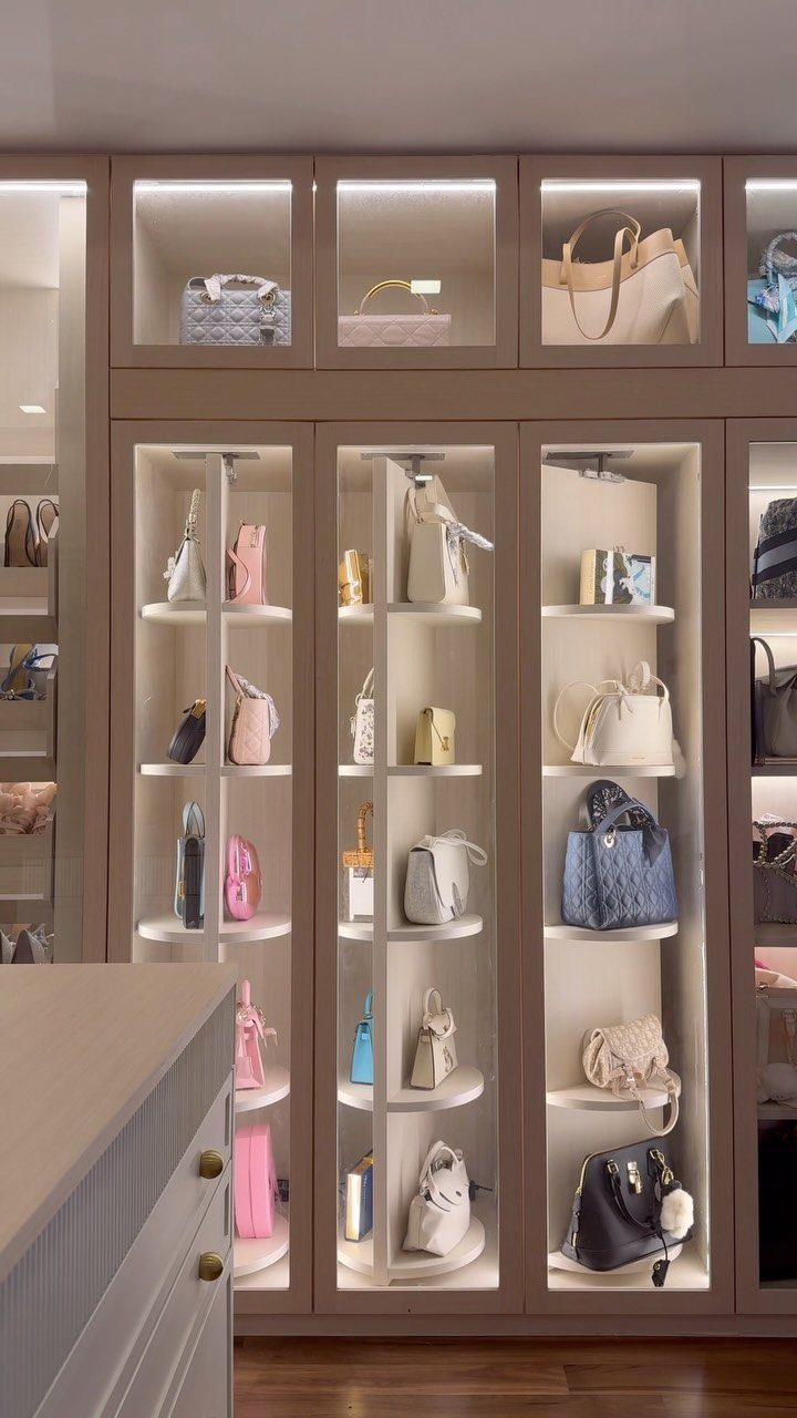 Luxurious walk-in closet with illuminated beige shelves displaying a collection of designer handbags.