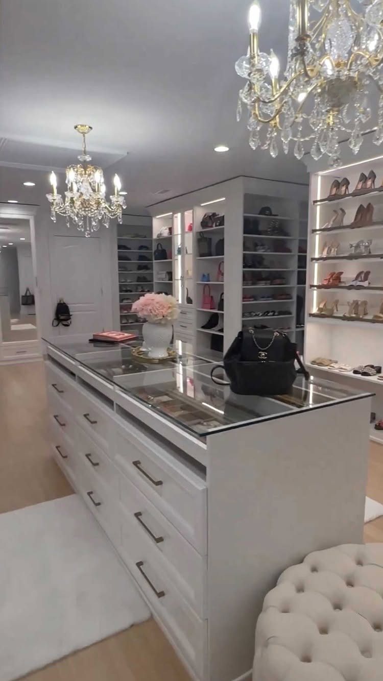 White walk-in closet with a central island and vertical LED strip lighting on shelves.
