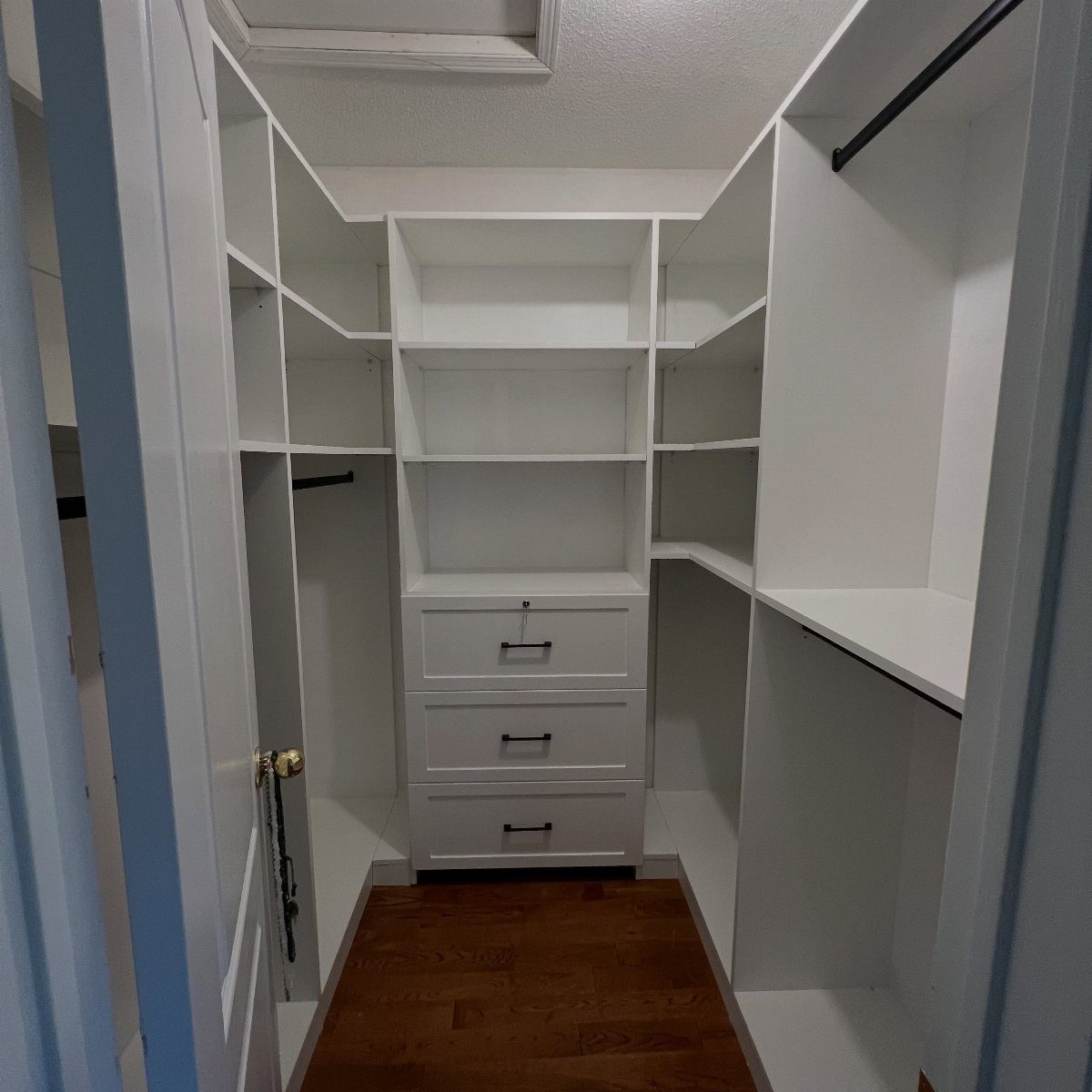 White walk-in closet with a U-shaped layout featuring built-in shelves and drawers.
