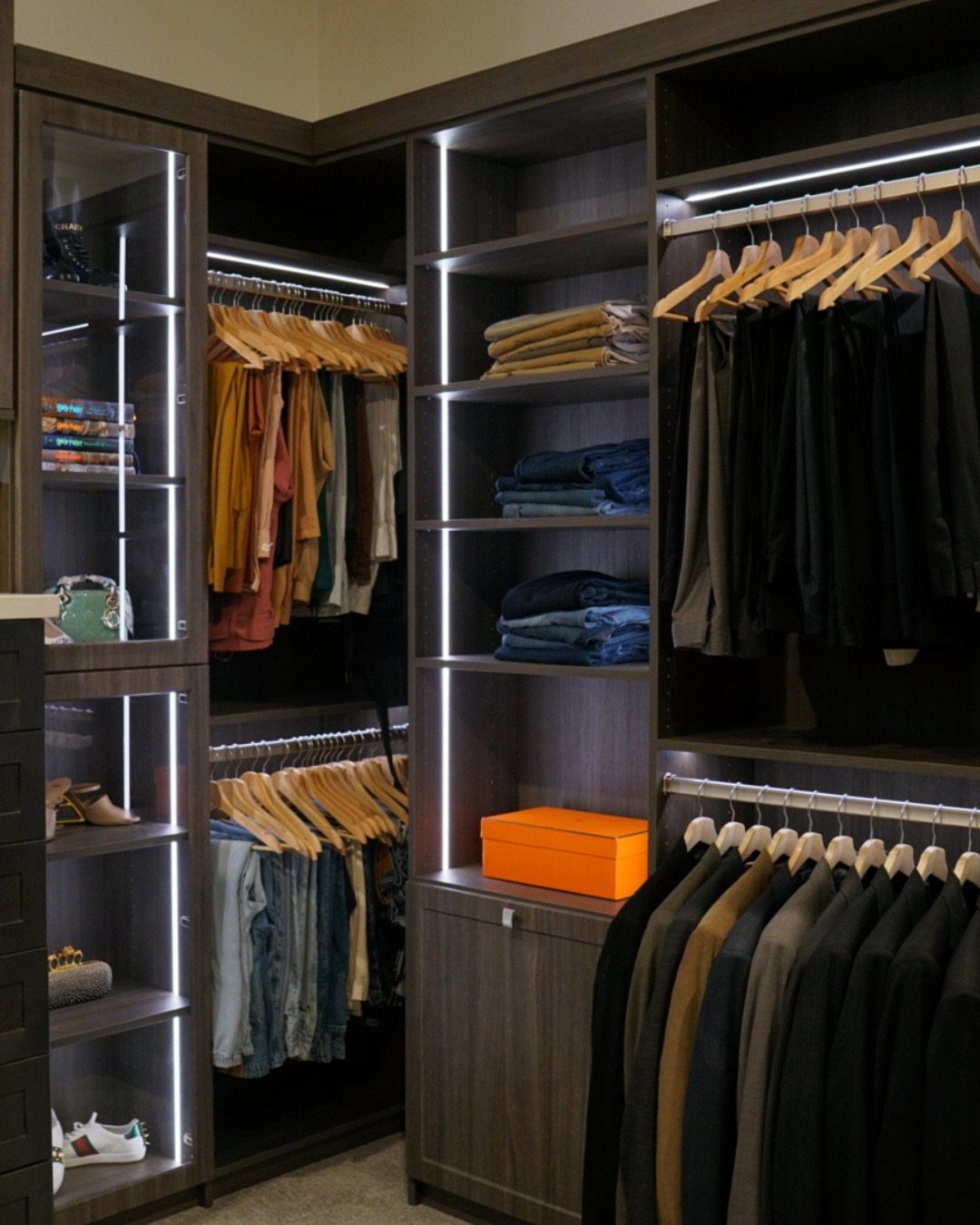 Modern walk-in closet with dark wood cabinetry and integrated LED strip lighting.