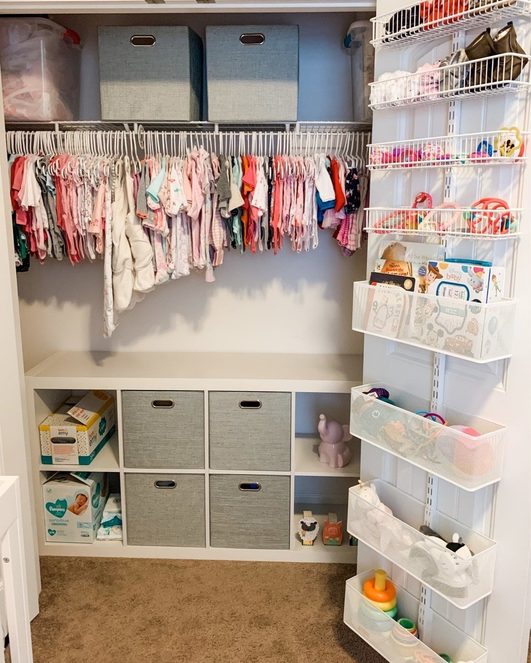 White cube shelf unit with grey bins in a baby's organized walk-in closet.