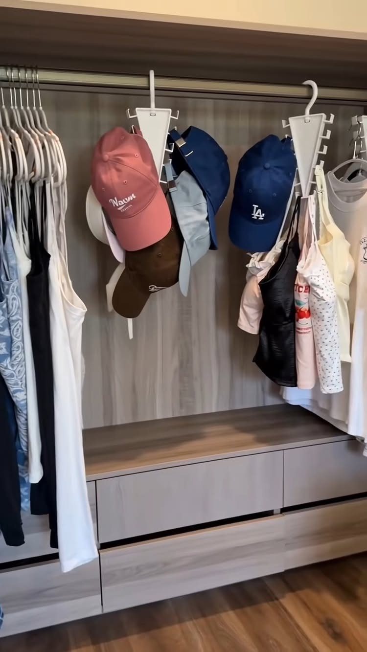 Walk-in closet with light wood cabinetry, hanging clothes, baseball caps, and built-in bench.