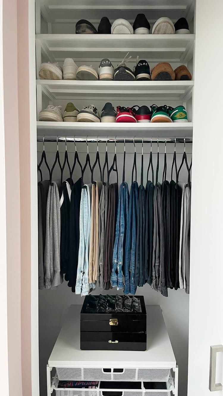 White built-in closet with organized shoe shelves, hanging pants, and storage bins.