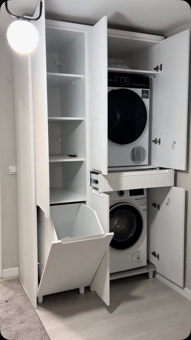 White built-in laundry cabinet with stacked washer dryer and pull-out hamper.