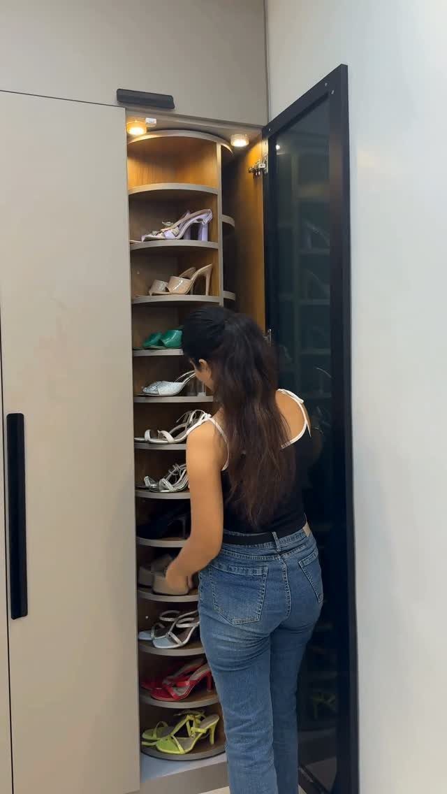 Woman selecting shoes from a curved rotating rack inside a modern closet