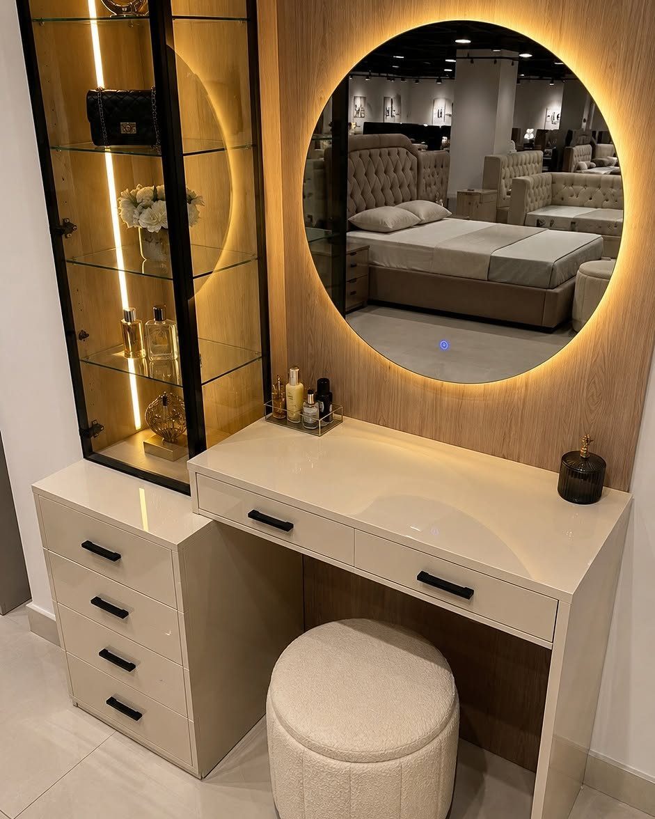 Modern vanity with round backlit mirror, white desk, and glass display cabinet.