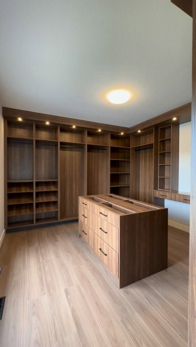 Walk-in closet with dark wood cabinetry and recessed ceiling lighting for illumination.