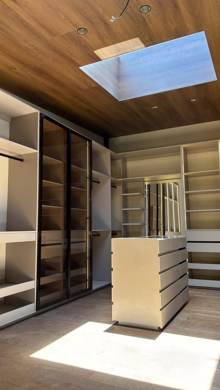 White central island with drawers in a modern walk-in closet with wooden ceiling.