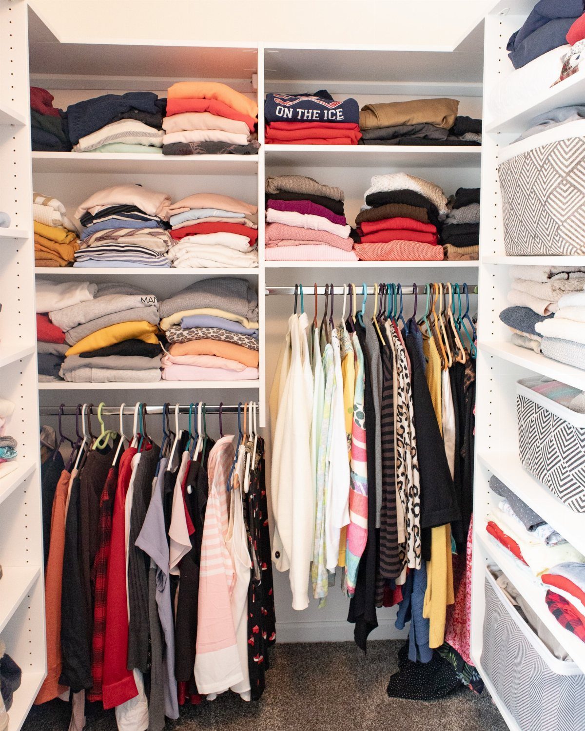 White built-in closet with organized sections for folded clothes and hanging garments.