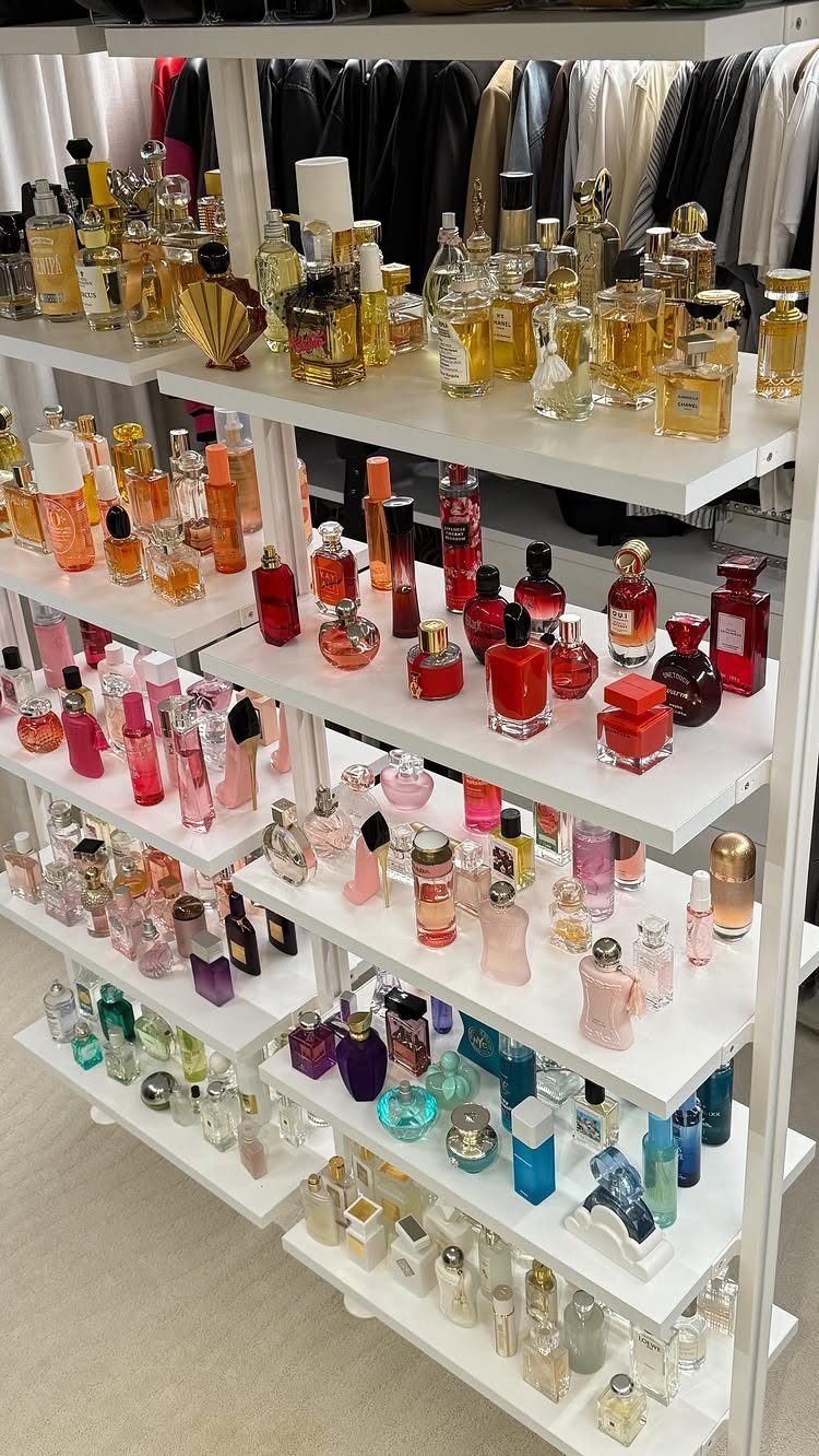 Perfume bottles of various colors organized on white shelves in a closet.