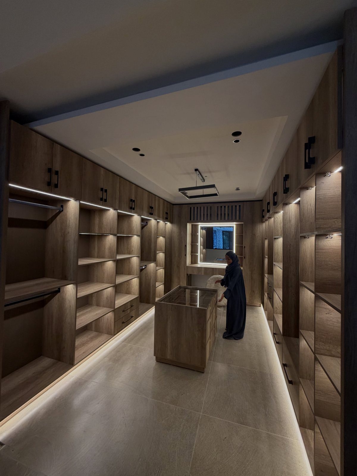 Modern walk-in closet with wood cabinetry, central island, and recessed ceiling lighting.
