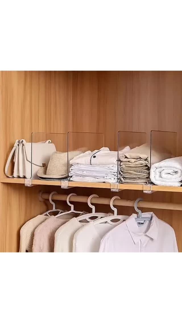 Clear acrylic dividers organizing folded clothes on a wooden closet shelf.
