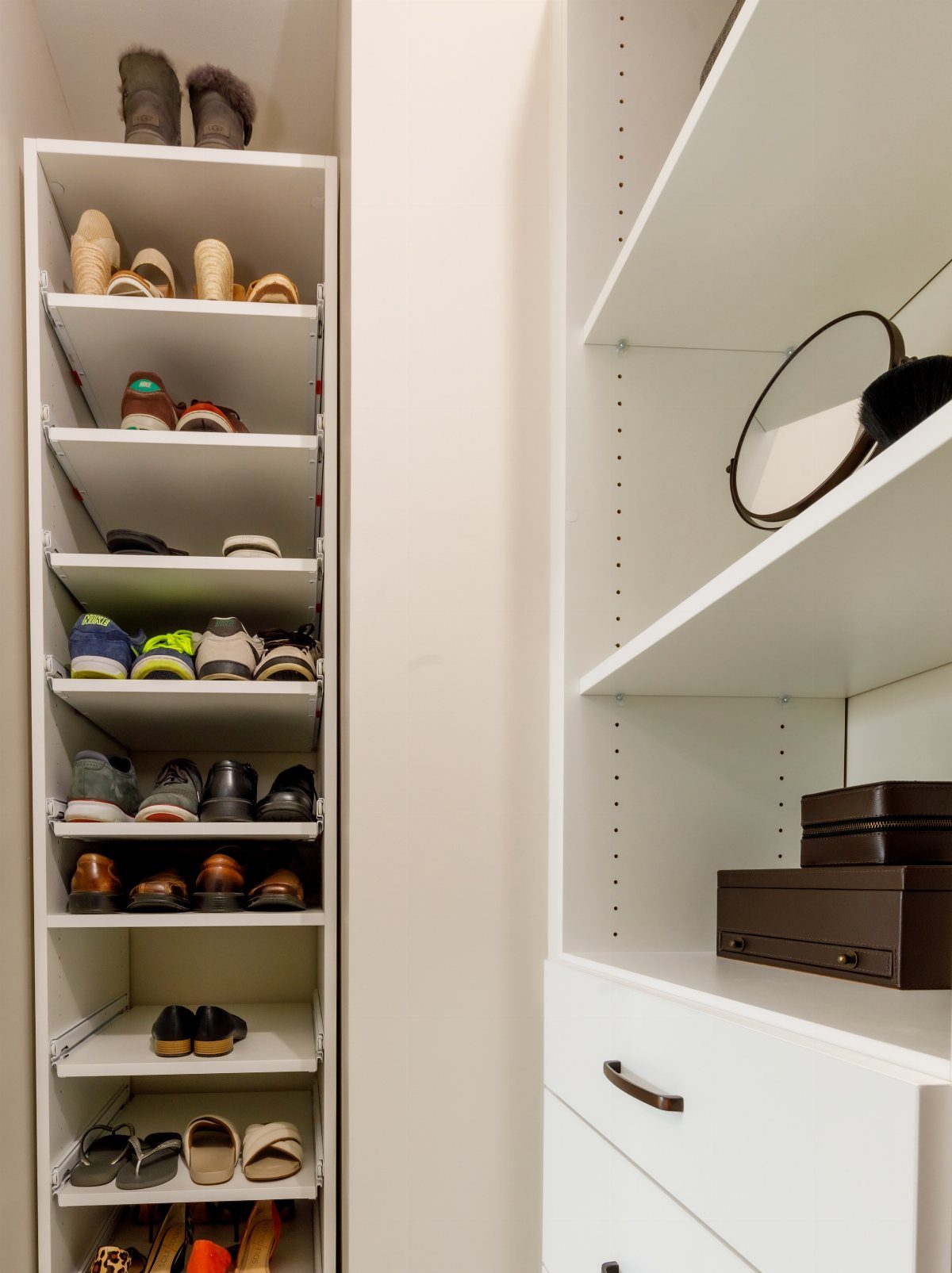 Tall white closet shelving unit filled with shoes and storage boxes.