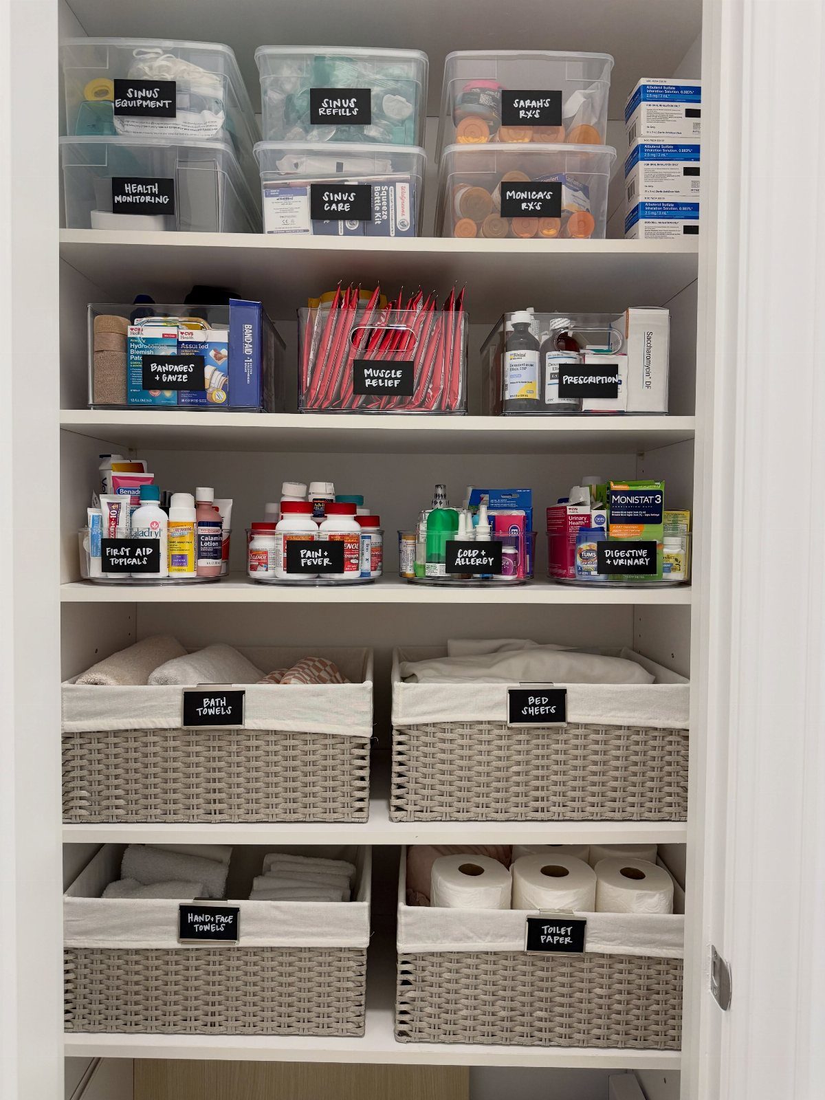 White closet shelves with labeled clear bins and woven baskets holding toiletries.
