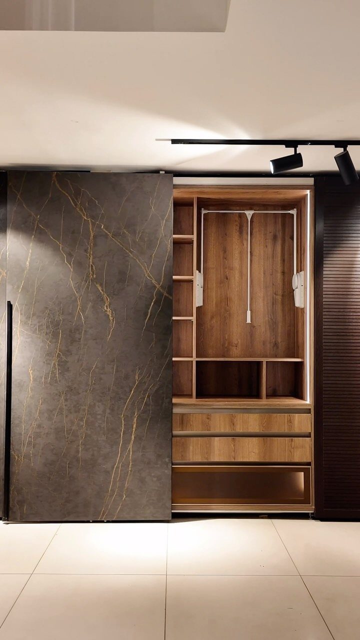 Modern wood-grain closet shelving with a hanging rod and dark marble sliding door.