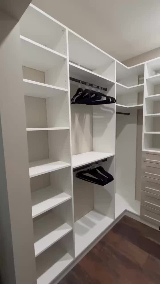White built-in closet system with open shelves, hanging rods, and integrated drawers.