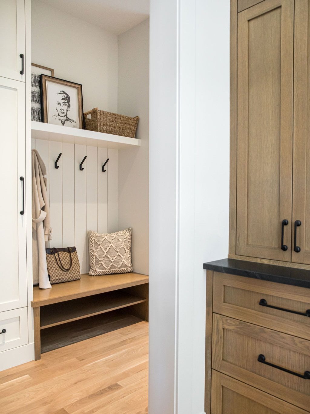 Wooden entryway bench with a cushion, hooks, and built-in storage shelving.