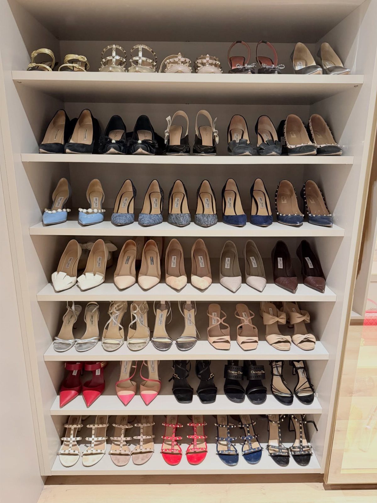 White built-in closet shelves neatly organizing rows of colorful women's high-heeled shoes.