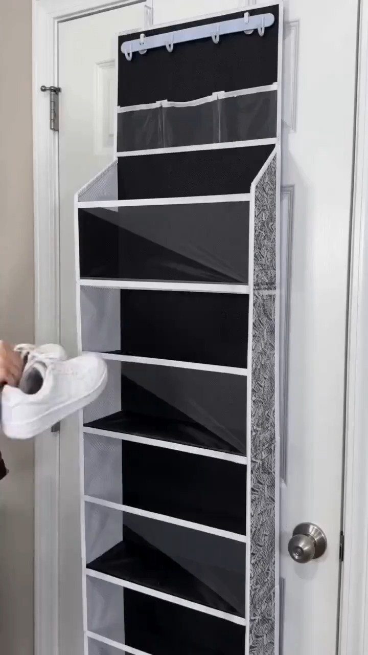 Hanging shoe organizer on a white door with a white sneaker being inserted.