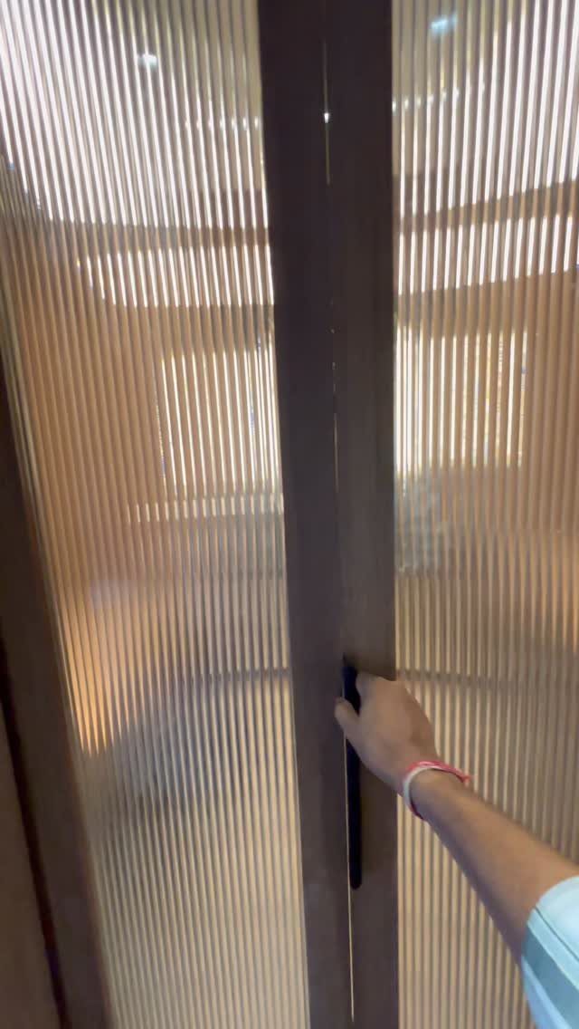 Hand opening a fluted glass closet door with a dark brown frame.