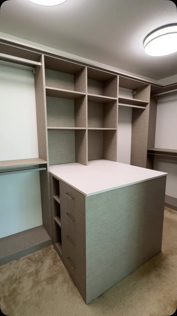 Walk-in closet featuring a light brown wooden peninsula with a white countertop.