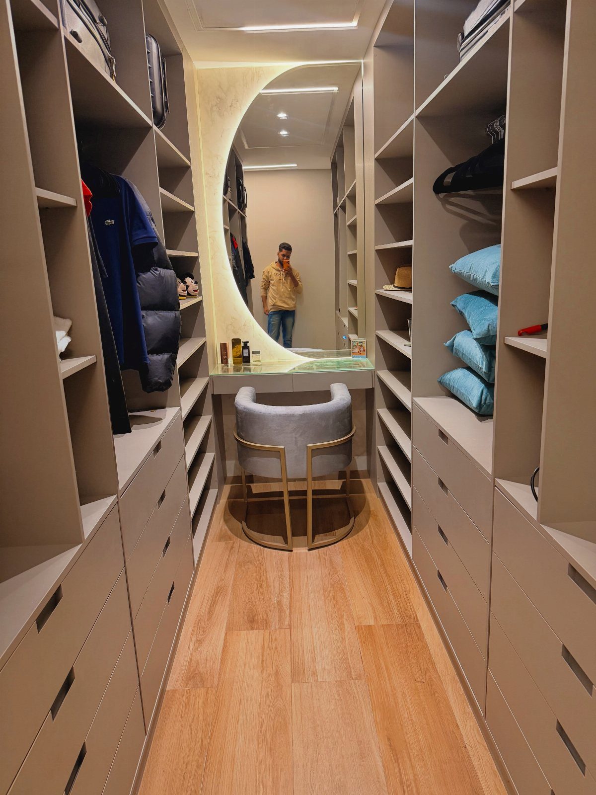 Circular backlit mirror above a vanity desk in a modern walk-in closet.