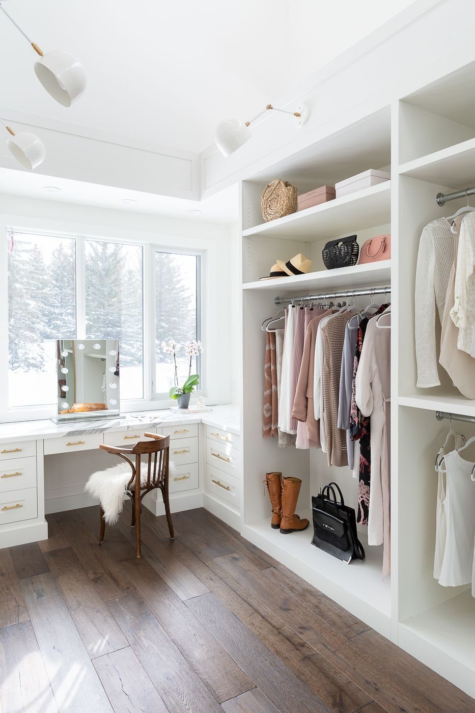 White walk-in closet with built-in shelves, hanging clothes, and a vanity desk.