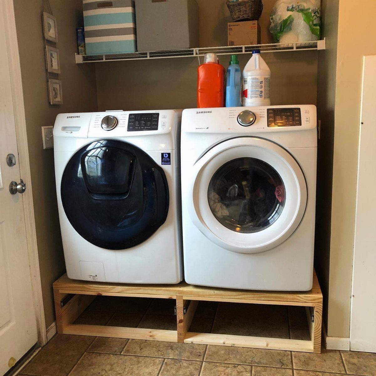 White washer and dryer sitting on a DIY wooden platform pedestal in laundry room