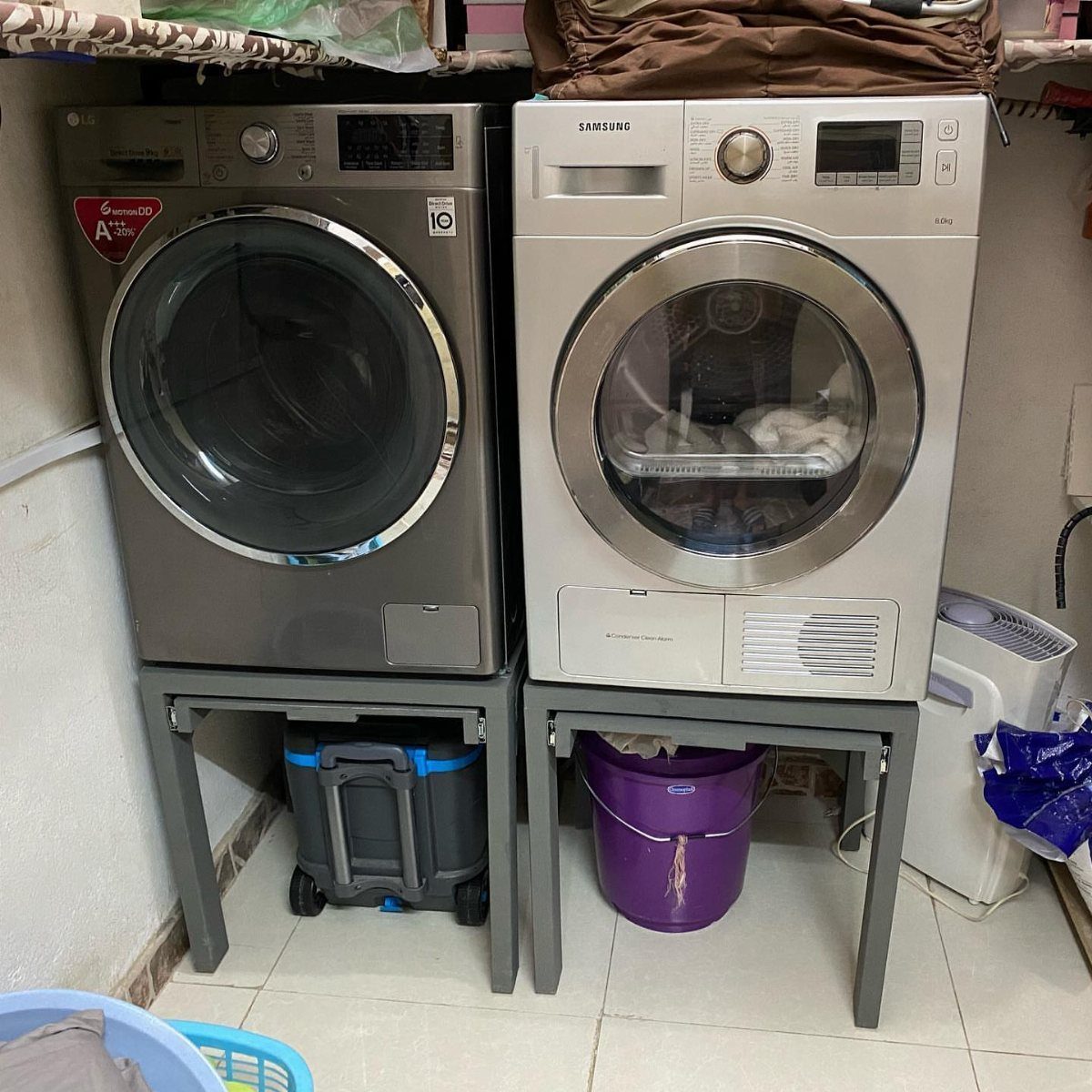Grey washer and white dryer elevated on grey metal frame pedestals in laundry room