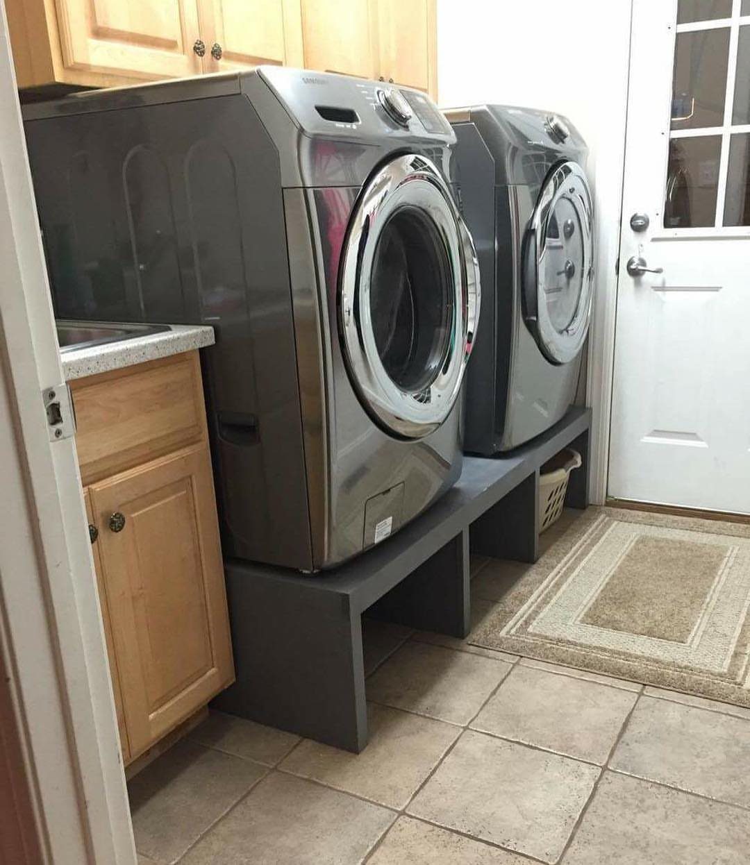 Grey washer and dryer elevated on a dark grey custom laundry pedestal platform.
