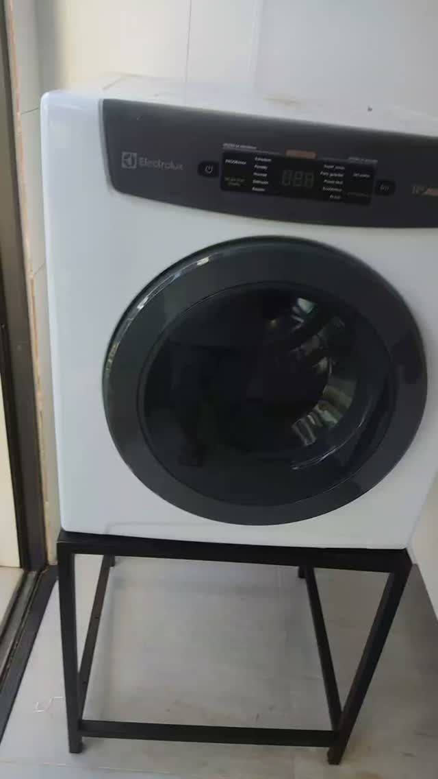 White front-loading washing machine elevated on a black metal rectangular stand.